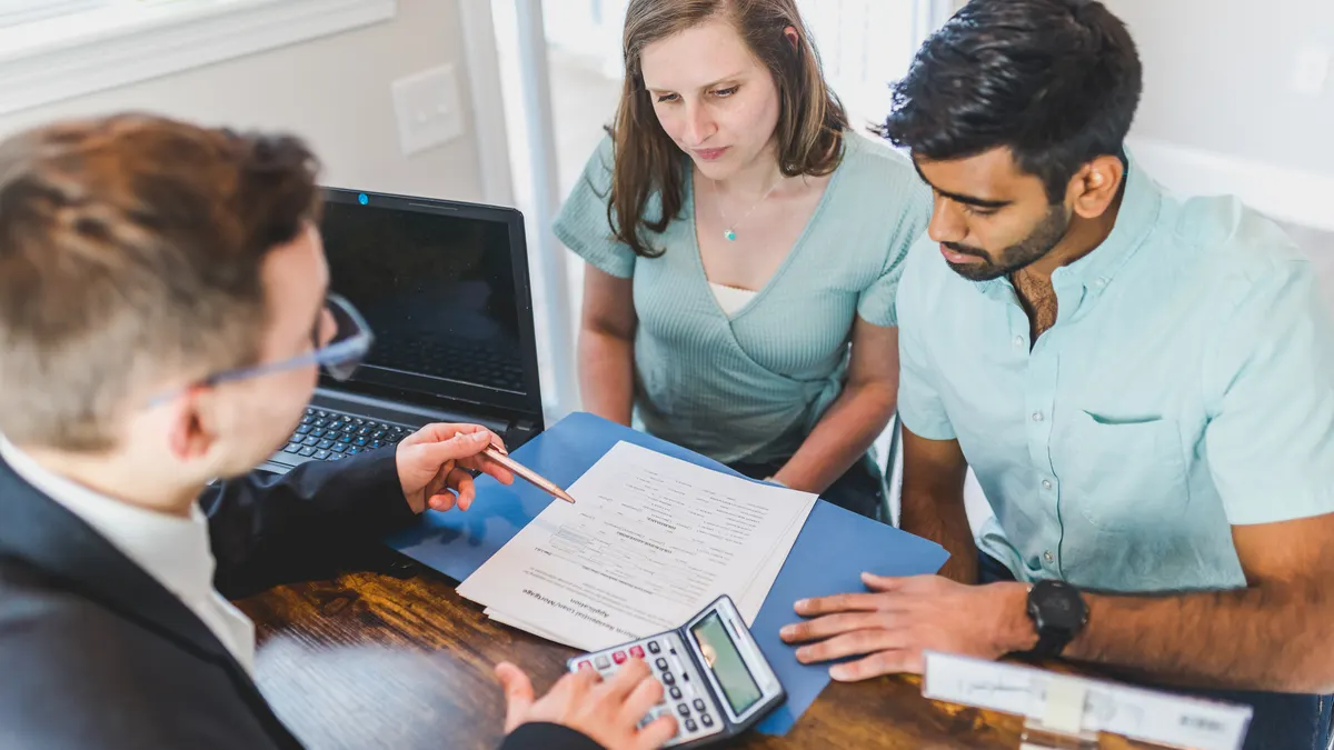 How Earnest Money Works When Buying a House Home buyers and agent discussing a contract at a table