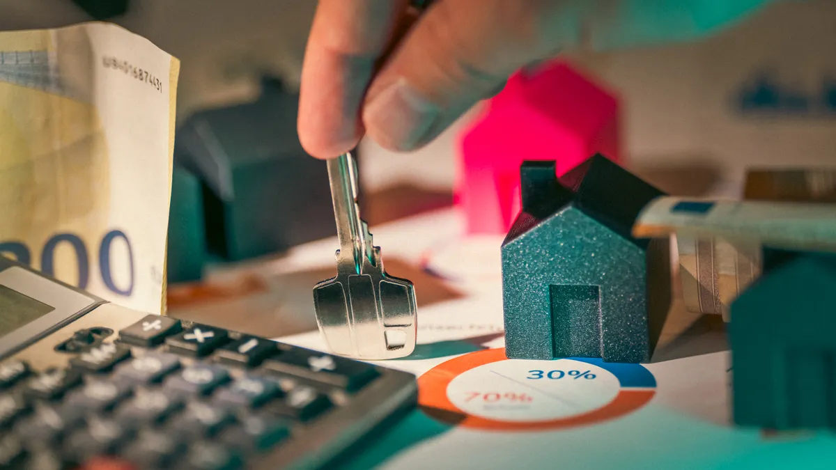How to Choose the Best Listing Price Strategy Hand holding house key over model homes and money