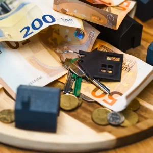 Model houses, coins, and euro notes on a tray