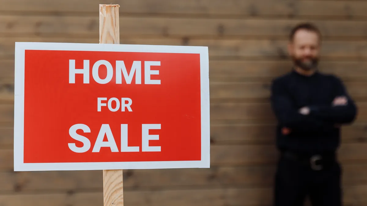 Home for sale sign with person behind it