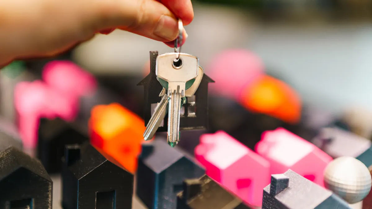 Hand lifting keys above miniature houses