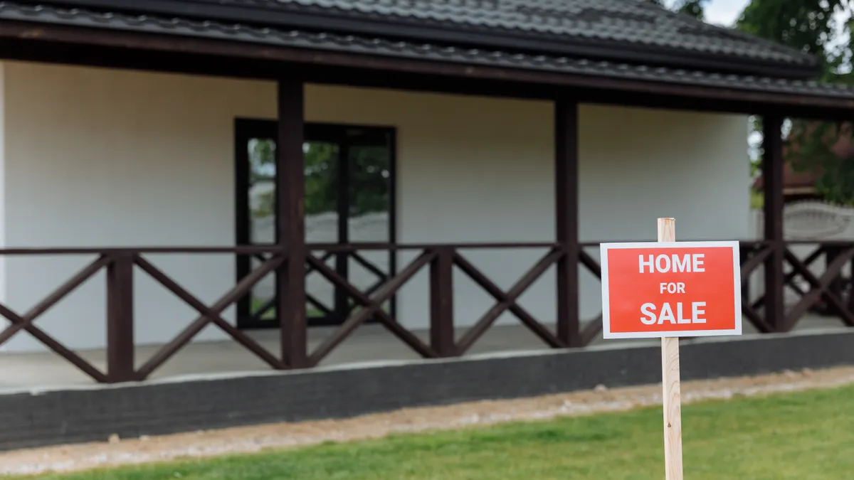 House with a HOME FOR SALE sign on the lawn
