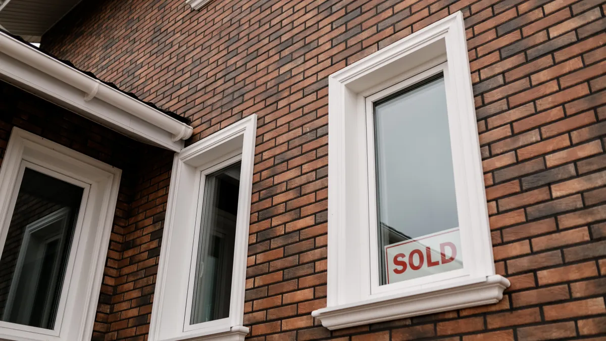 brick house with sold sign in window